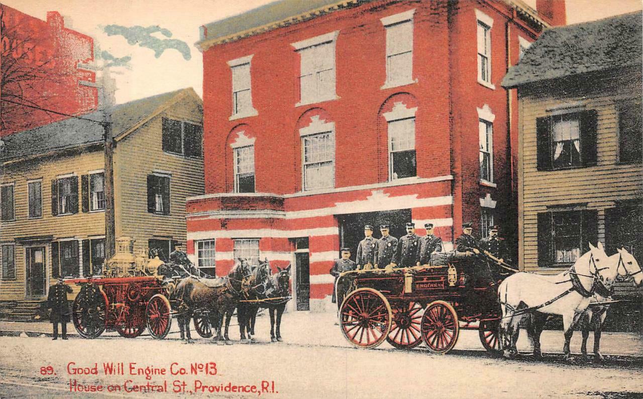 A three-story former fire house. The first story has alternating courses of red brick and granite with a central doorway for older fire apparatus to come and go. The redevelopment cleaned up the brick and added red-painted framed windows with decorative grates featuring flame patterns.