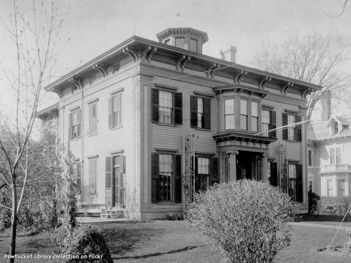 A three story, Greek-temple-looking large house with two-story porch and symmetrical façade. The roof seems flat, and a large ell projects off the back of the house. More descriptions are included in the descriptions within the article.